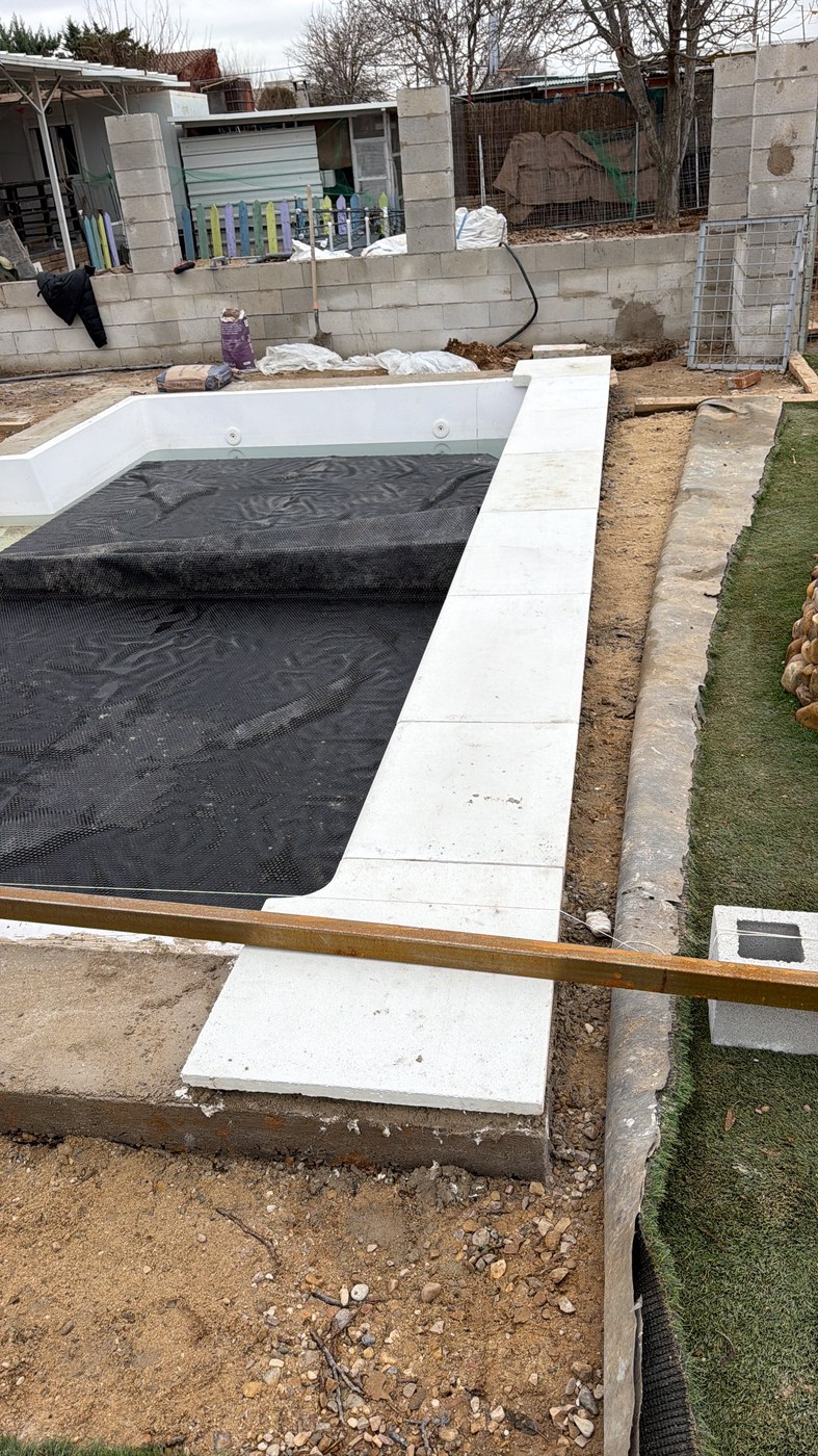 Coronación de piscina rectangular en piedra artificial blanca con corte a inglete, vaso en fase de impermeabilización